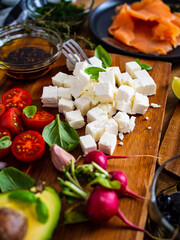 Breakfast - smoked salmon, feta cheese, avocado and vegetable salad on wooden table
