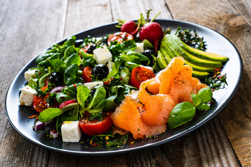 Breakfast - smoked salmon, feta cheese, avocado and vegetable salad on wooden table
