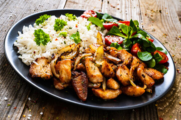 Chicken meat with rice and vegetables on wooden table

