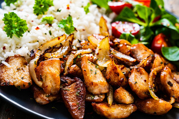 Chicken meat with rice and vegetables on wooden table
