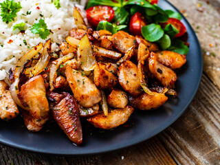 Chicken meat with rice and vegetables on wooden table
