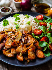 Chicken meat with rice and vegetables on wooden table
