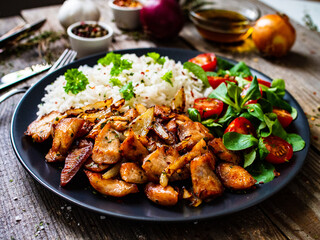 Chicken meat with rice and vegetables on wooden table
