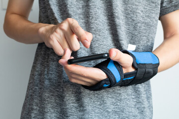 Hand injury. Broken wrist and arm with bandage. Using wrist immobilizer after hand injury. Retainer for recovery and release pain in the wrist and hand. Wrist pain after overuse mobile phone.