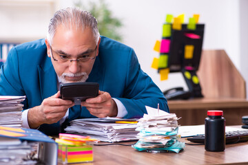 Old employee working in the office in conflicting priorities