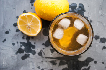Homemade lemonade with ice in a glass. Glass, lemons and drops on a gray background,top view, place for text.