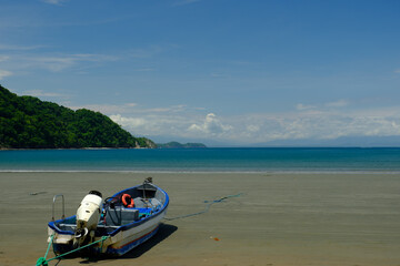 Fototapeta na wymiar Tied down small Fishing boat on a wide expanse of empty beach on the Gulf of Nicoya in Costa Rica