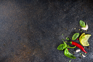 Assortment of spices, herbs and greens. Ingredients for cooking. Food background. Black stone table, Copy space for text. Top view.