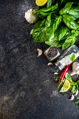 Assortment of spices, herbs and greens. Ingredients for cooking. Food background. Black stone table, Copy space for text. Top view.