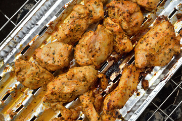 Kawałki kurczaka w panierce na aluminiowej tacy podczas smażenia na grilu. 