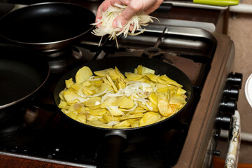 the chef adds chopped onions to the potatoes. cooking process.