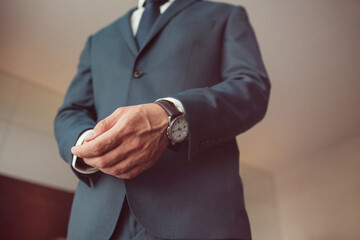 stylish groomsmen helping happy groom getting ready in the morning for wedding ceremony. luxury man in suit in room. wedding day.