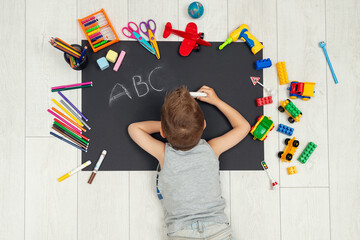 Kid draws on a black sheet of paper. Boy writing a letter