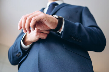 stylish groomsmen helping happy groom getting ready in the morning for wedding ceremony. luxury man in suit in room. wedding day.