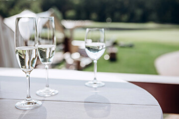Table setting for a wedding party. a round table with a white tablecloth, glasses, white plates in the rays of the setting sun.