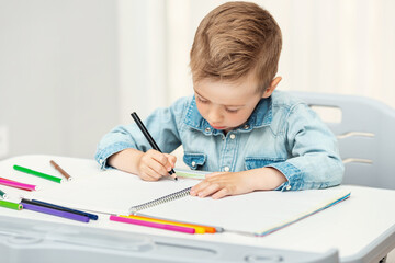 Portrait of child boy drawing with colorful pencils