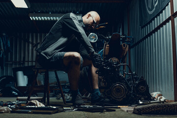Young man repairing his motorcycle engine in the garage. The motorcycle engine is disassembled....