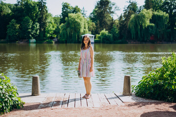 Sofia Park, Uman. Young woman with a tourist map by the lake. A woman in a colored dress walks along the river. Girl on a background of a white gazebo near the lake.