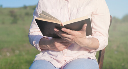 A young girl holds a book in her hands. Outdoors. Spring