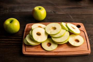 Pile of fresh green apples ready to be put on fruits dryer on cutting board