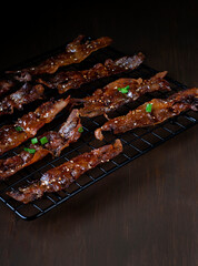Roasted bacon in sweet maple syrup glazing topped with sesame seeds and herbs on the black lattice