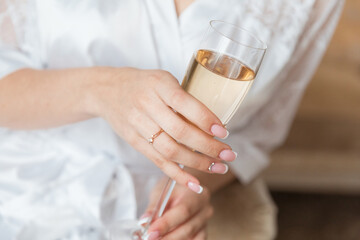 bride's hand with beautiful manicure and engagement ring and champagne