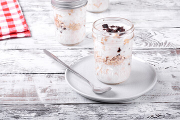 Overnight oats with yogurt topped with chocolate chips on the white wooden table