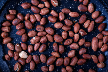 Roasted peanuts on the black frying pan. Top view. Copy space