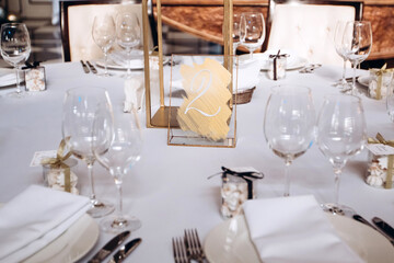 Table setting for a wedding party. a round table with a white tablecloth, glasses, white plates in the rays of the setting sun.