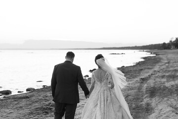 Newly married couple walking away together on the beach