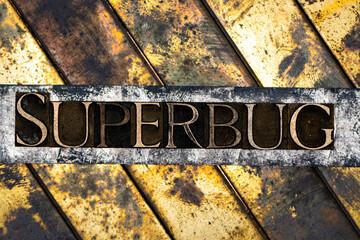 Photo of real authentic typeset letters forming Superbug text on vintage textured silver grunge copper and gold background