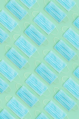 Surgical masks arrange in pattern on green background