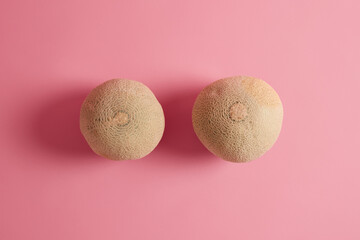 Two whole ripe delicious cantaloupe melons photographed from above over rosy background. Summer...