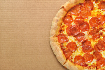 Pepperoni pizza with sausages on brown corrugated fiberboard background.