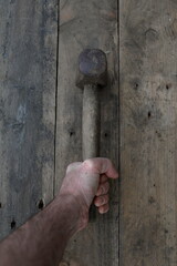 Hand Holding Old Hammer on Wood