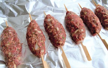 Juicy meat kebabs with spices on wooden skewers. On the background of aluminum foil for baking