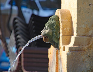 BALLUTA BAY, ST JULIANS, MALTA - OCTOBER 31ST 2019: Water flows from the mouth of a lion's mouth on...