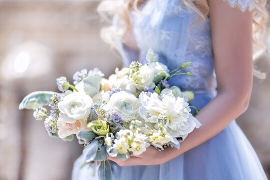 A bride in a blue wedding dress holds a wedding bouquet in her hands. Large beautiful Bridal bouquet of white roses and peonies.