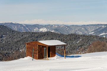 Wooden gatehouse on the mountain. A house on the edge of the ski slope. Winter view of the Caucasian ridge.