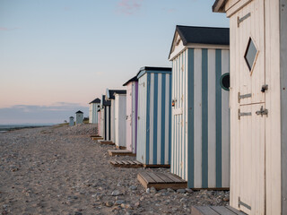 Tiny striped beach huts at sunset