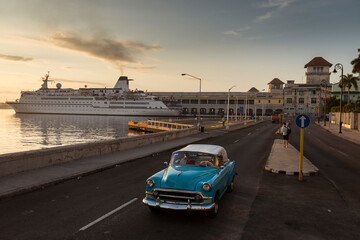 Old car on Malecon street of Havana with sunrise in background. Cuba