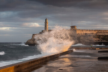 Big waves on Malecon streets during sunrise with storm clouds in background. Havana, Cuba