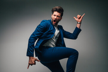 Happy young businessman jumping in the air on a gray background.