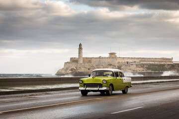 Old car on Malecon street of Havana with storm clouds in background. Cuba