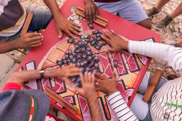 Peoples hand on a table playing domino in the street of Trinidad, Cuba