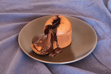 homemade chocolate fondant cake from which lies chocolate lies on a brown plate