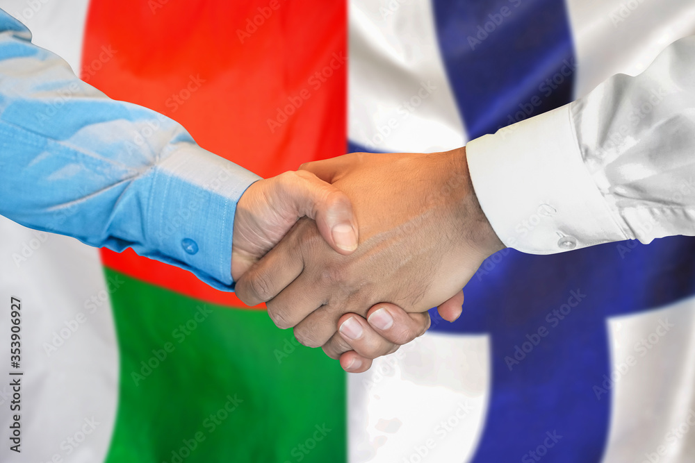 Wall mural handshake on madagascar and finland flag background. support concept.