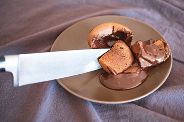 a large knife cuts homemade chocolate fondant cake from which chocolate flows