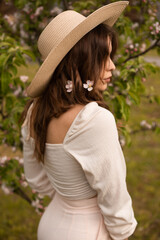 Long-haired girl in a hat in an Apple orchard in spring