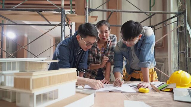 Serious discussion scene of Asia architects planning of house renovation with blueprint indoor, working confliction, home interior designer, home improvement, real estate development industries.